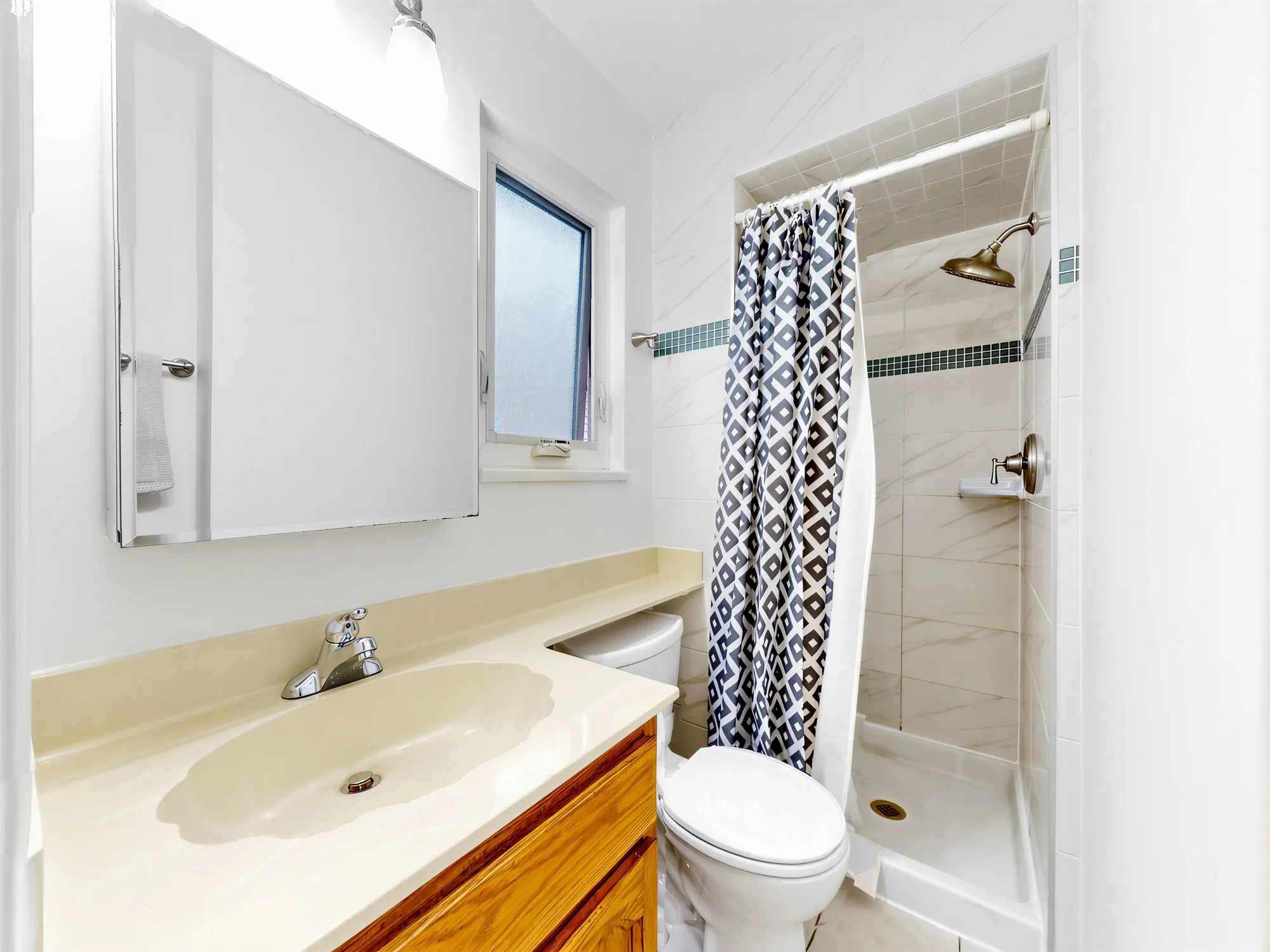 A bathroom with a shower behind a curtain and a window with obscured glass