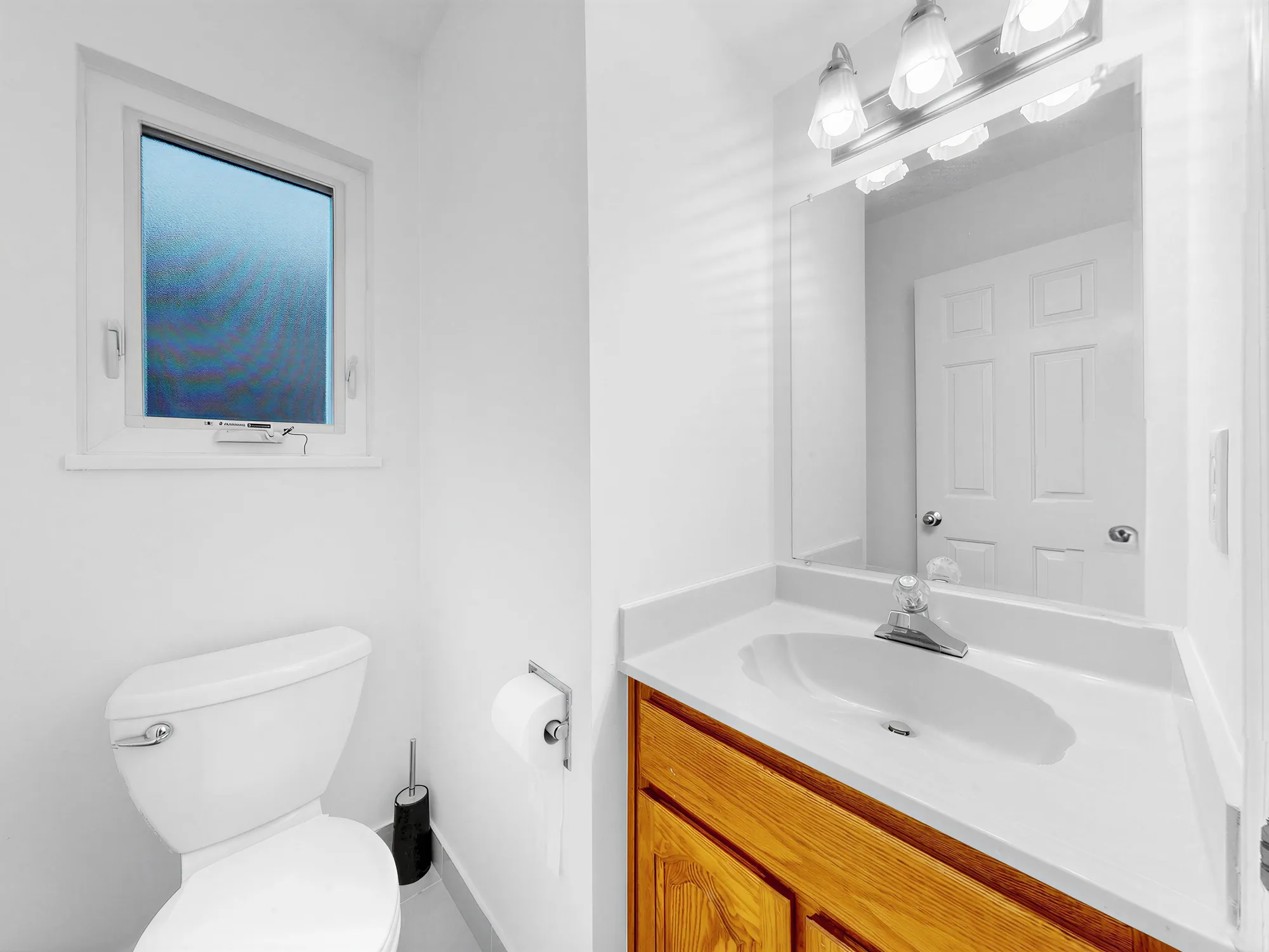 A small bathroom with a vanity, mirror and window