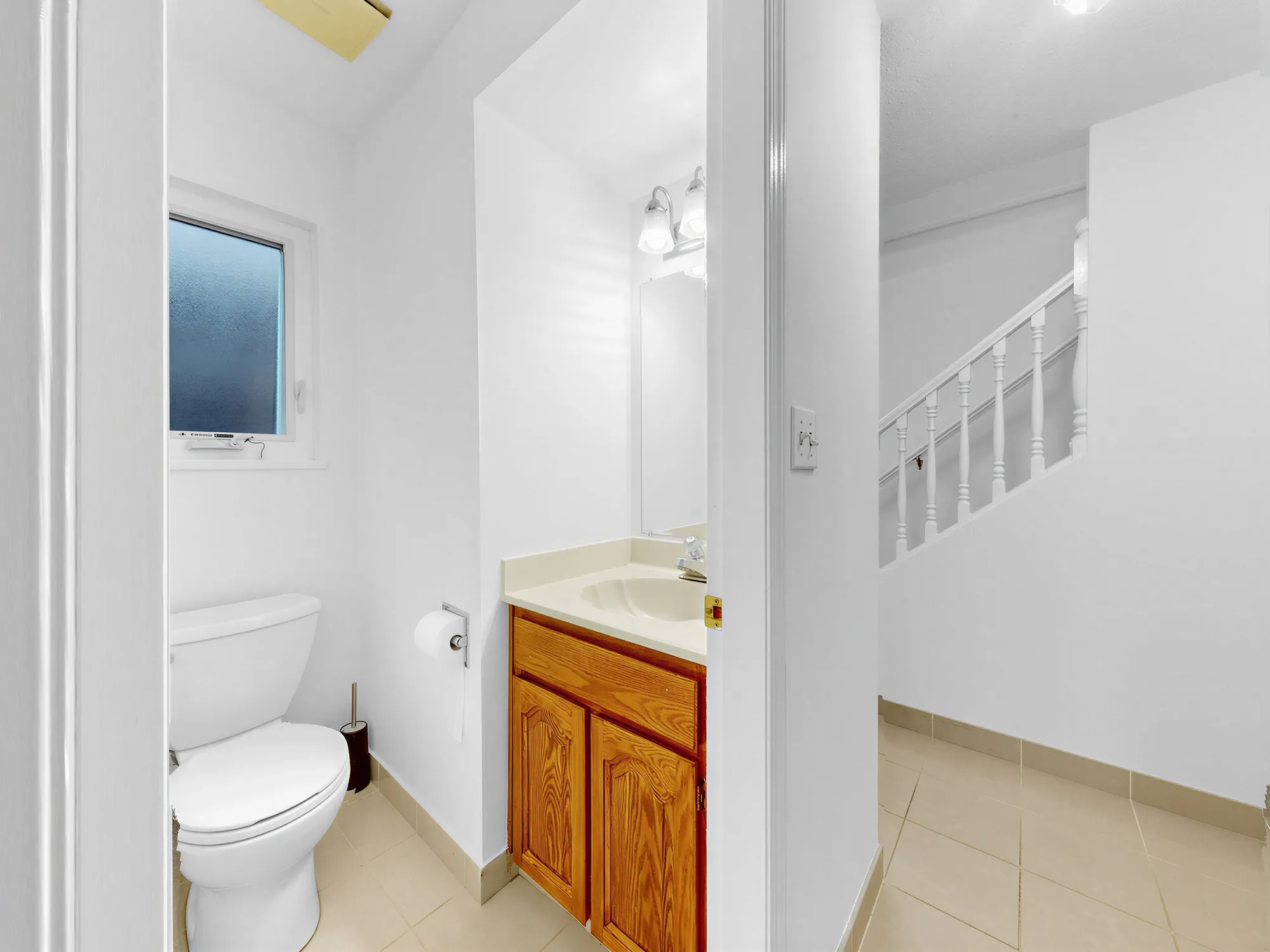 The same small bathroom, with the staircase visible through the door