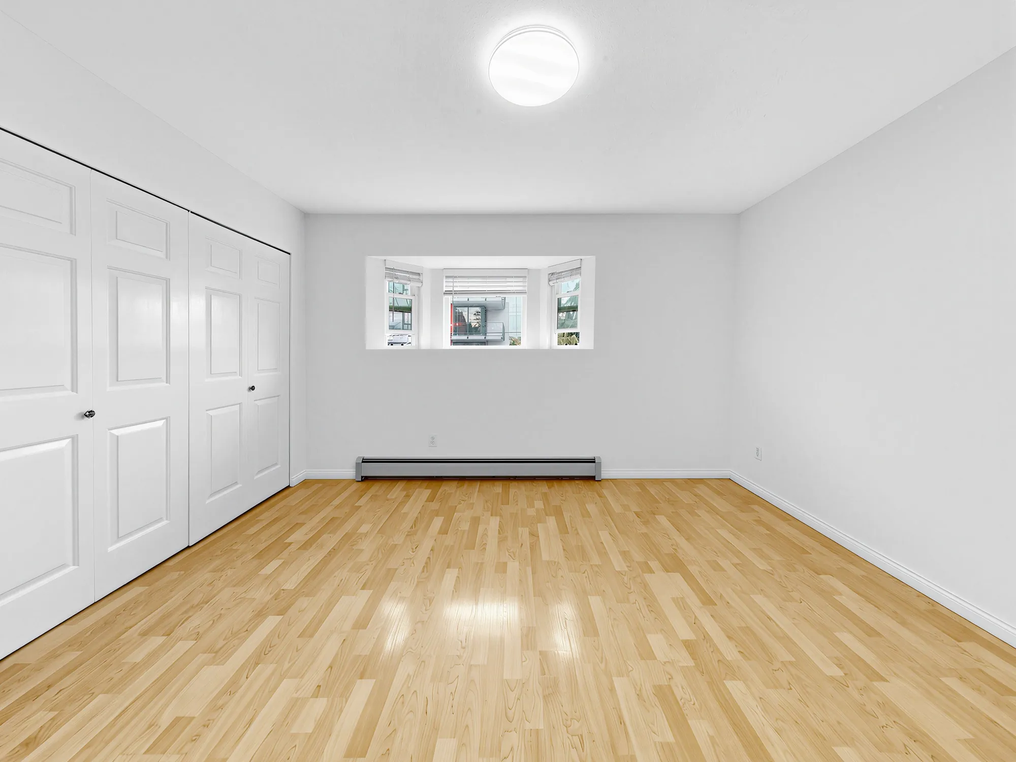 A bedroom with a bay window and a run of closet doors along one wall