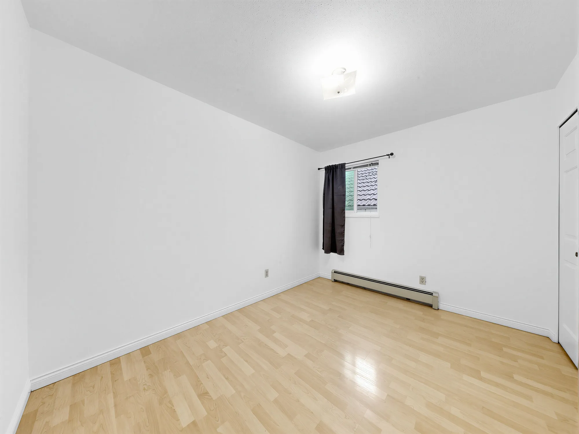 A bedroom with a window and a baseboard heater