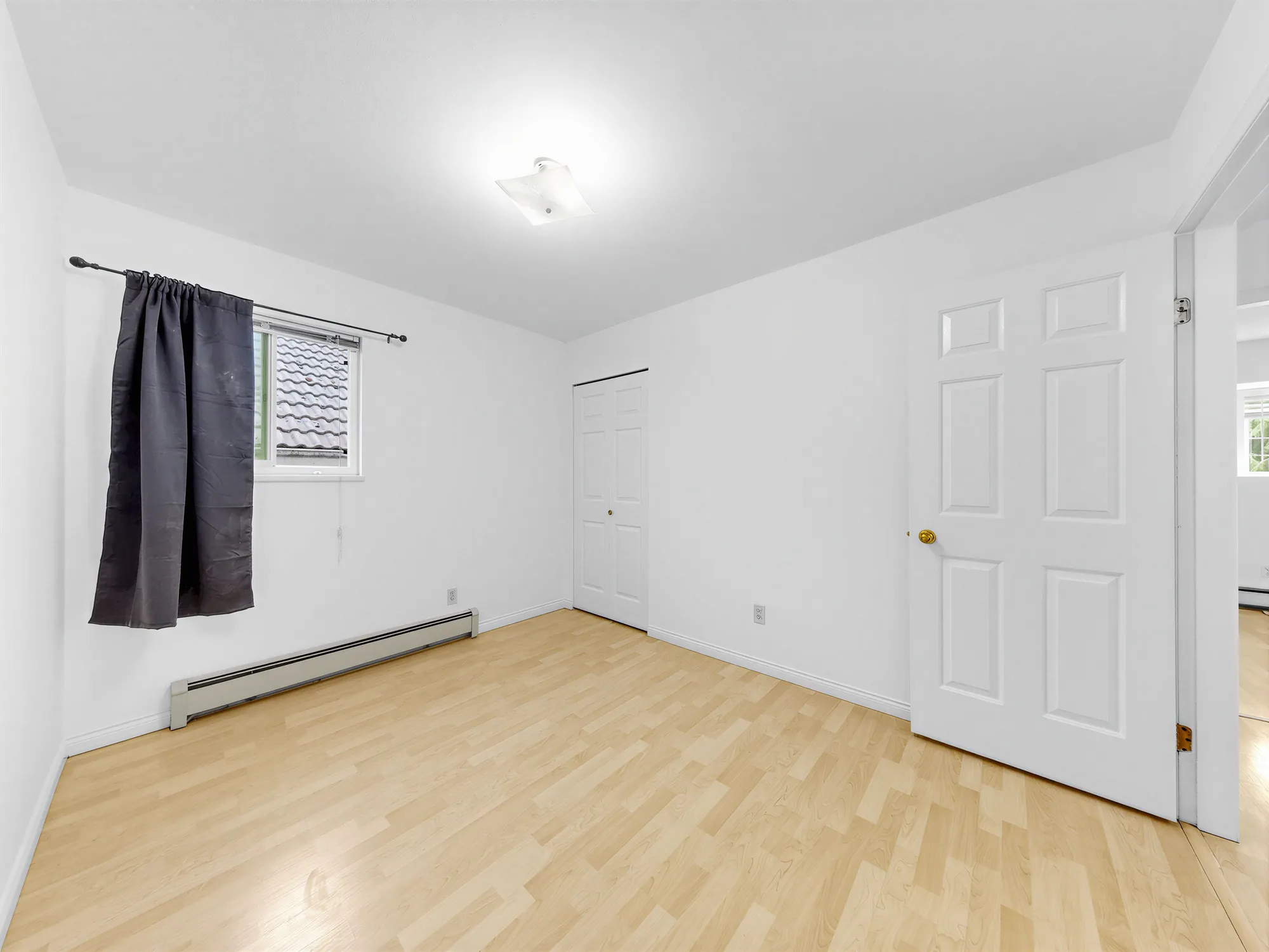 A bedroom with a door to the hall and a window to the left