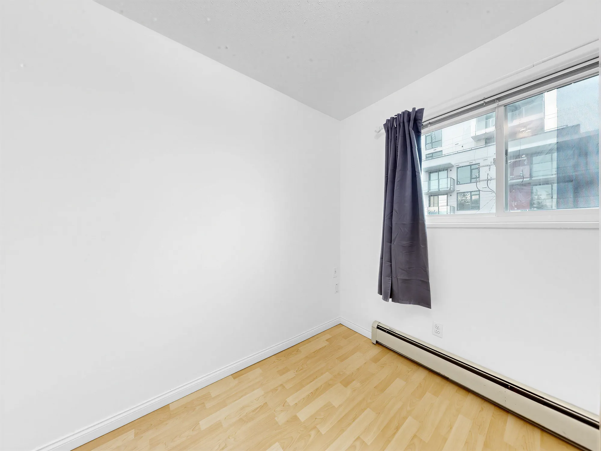 A bedroom whose window looks out at the neighbouring apartment building