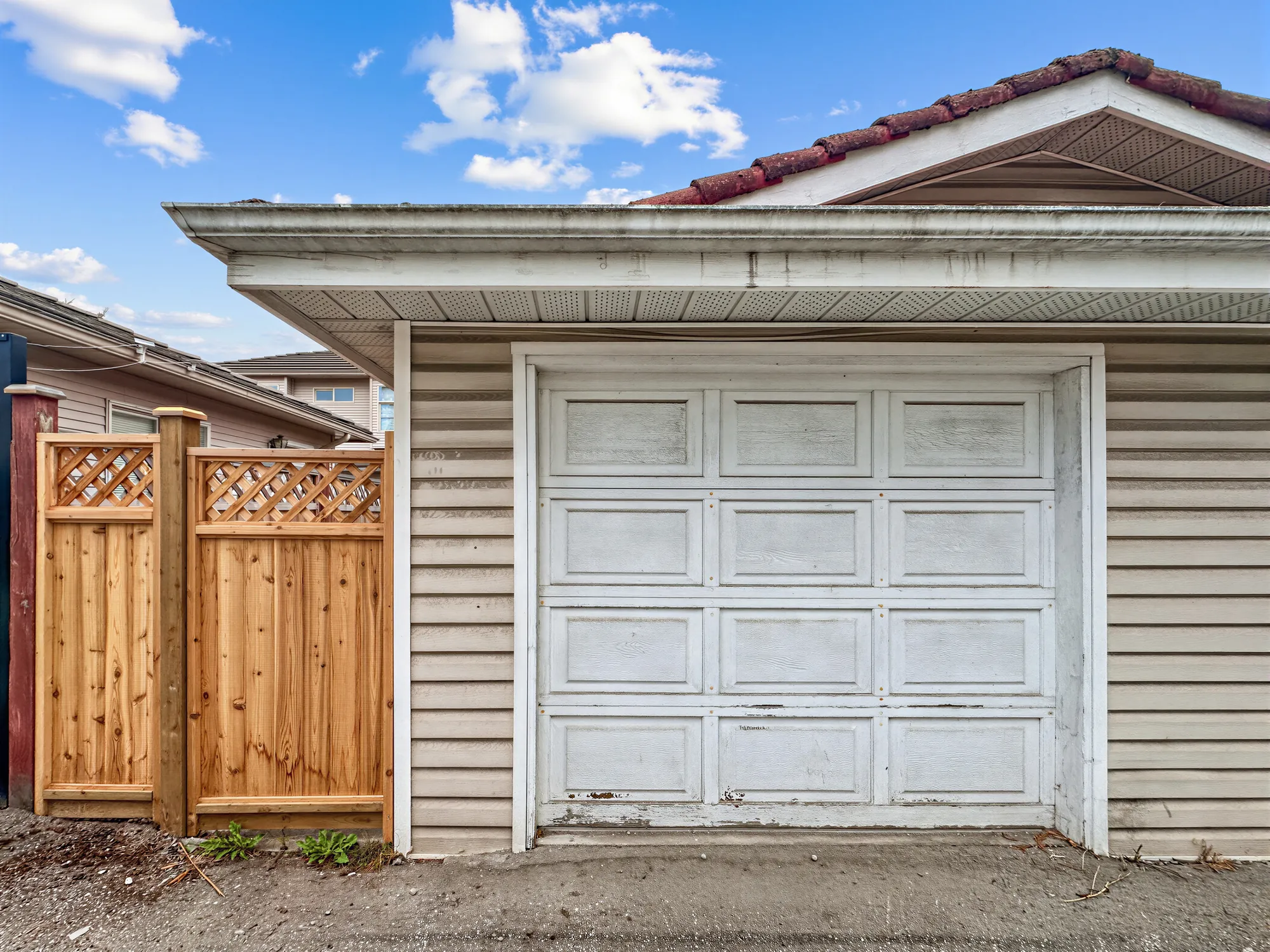 A single garage door off the lane beside a wooden fence