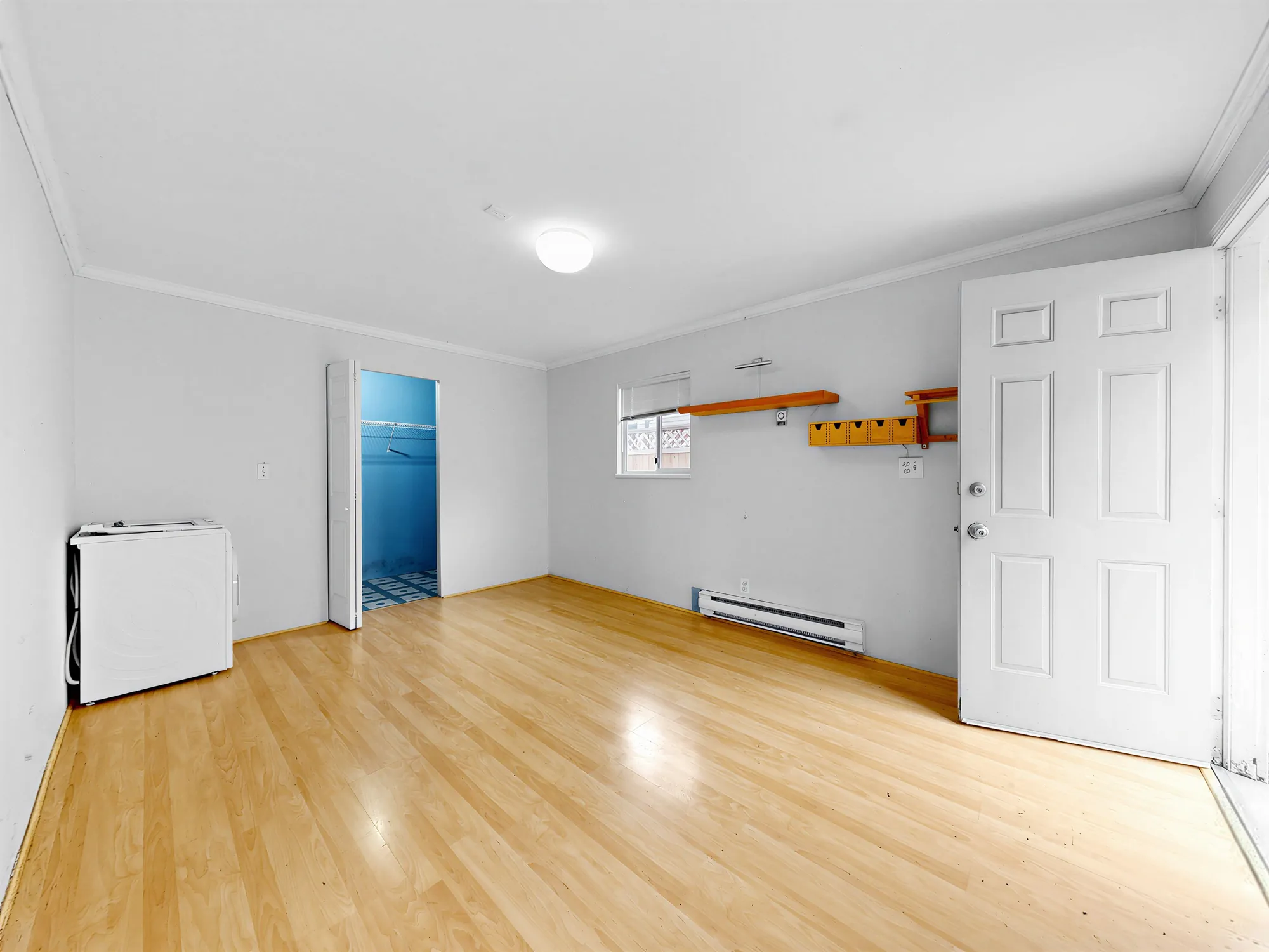 Inside the guest house: an empty room with a laminate floor, an exterior door and a walk-in closet