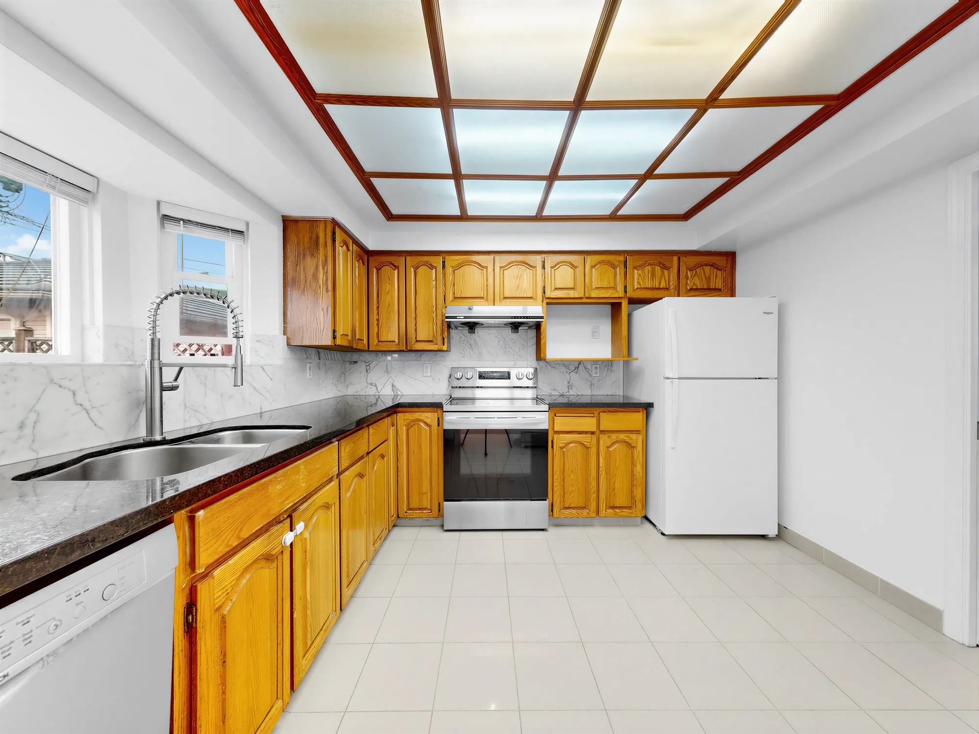 The kitchen with oak cabinets, a tiled floor and a window over the sink
