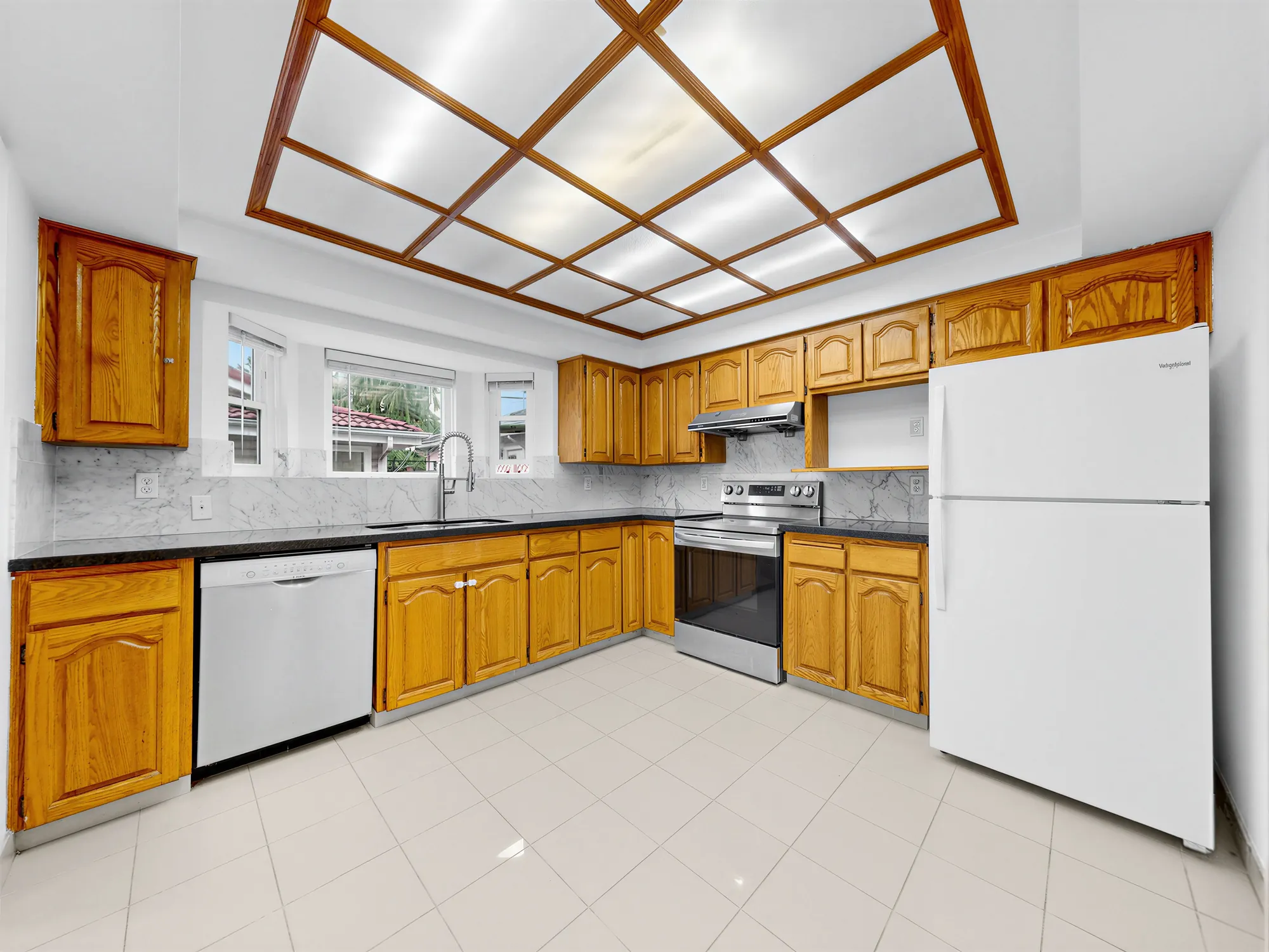 The kitchen from the opposite corner, showing the full run of cabinets and the refrigerator