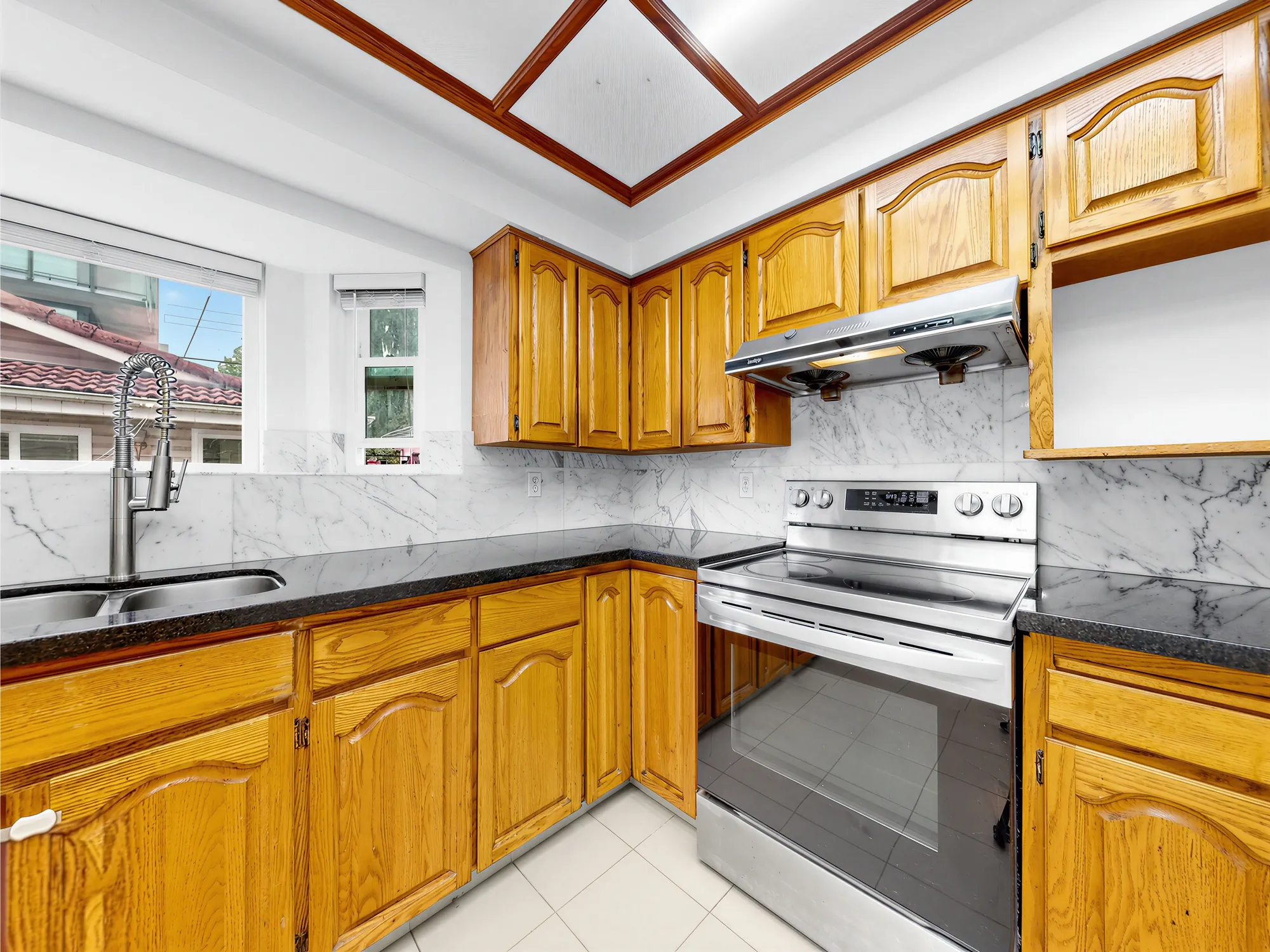 The range and hood against a marble-patterned backsplash