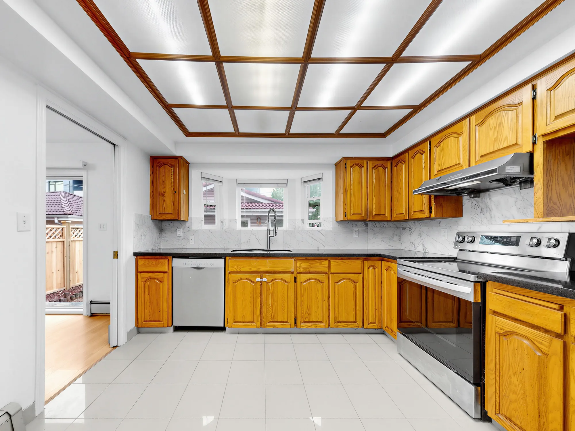 The kitchen seen from the hall doorway, with the panelled light ceiling above