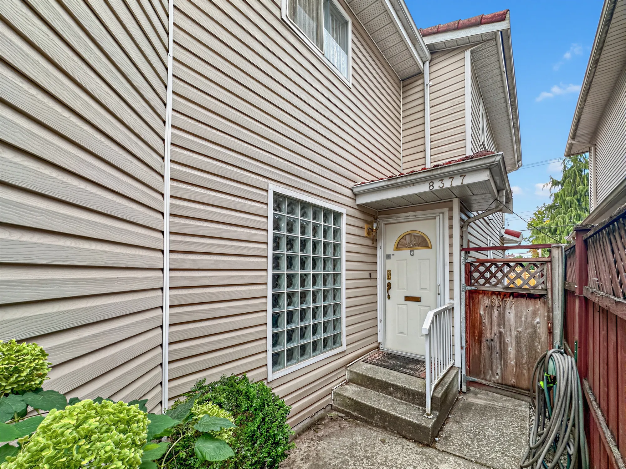 The side of the house with a white door and steps up to it